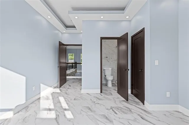 a view of a hallway with wooden floor and a bathroom