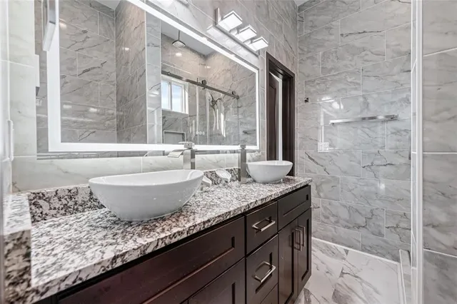 a bathroom with a granite countertop sink and a large mirror