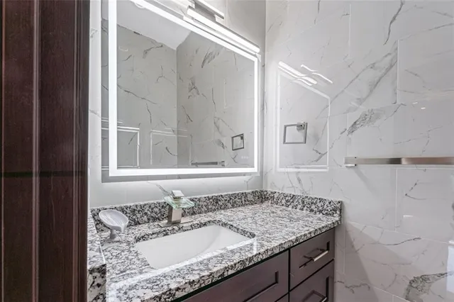a bathroom with a granite countertop sink and a mirror