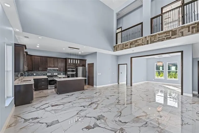 a kitchen with stainless steel appliances kitchen island granite countertop a refrigerator and a stove top oven