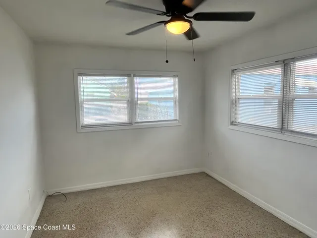 an empty room with a window and a fan