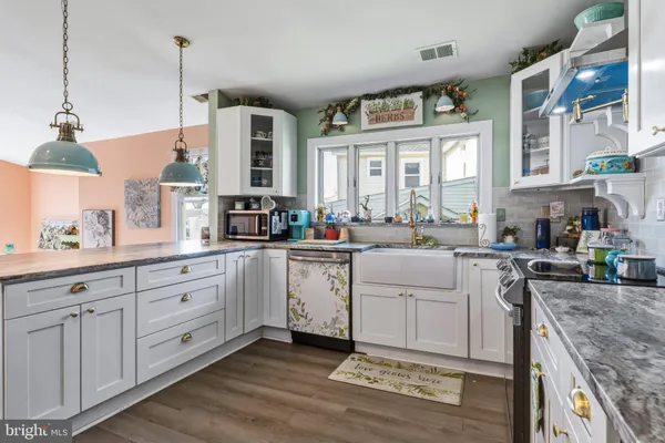 a kitchen that has a lot of white cabinets and wooden floor