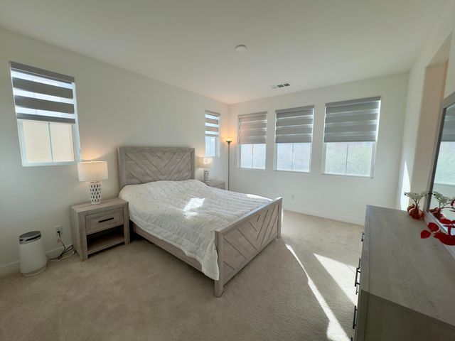 a bedroom with a bed and a flat tv screen on the dresser
