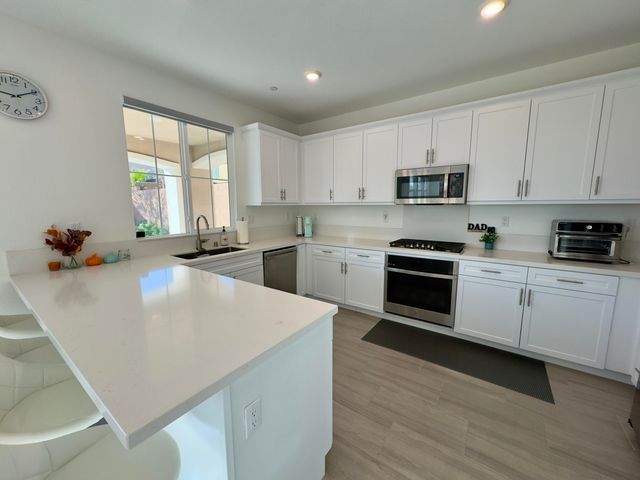 a kitchen with stainless steel appliances white cabinets a sink a stove a refrigerator and cabinets