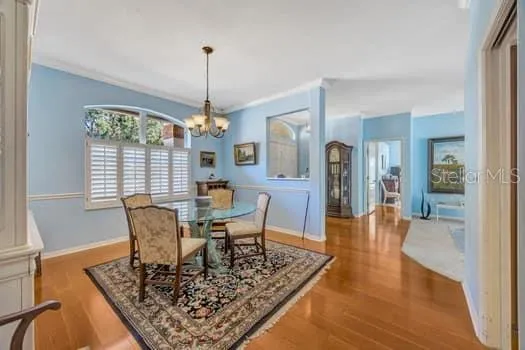 a dining room with wooden floor a chandelier a wooden table and chairs