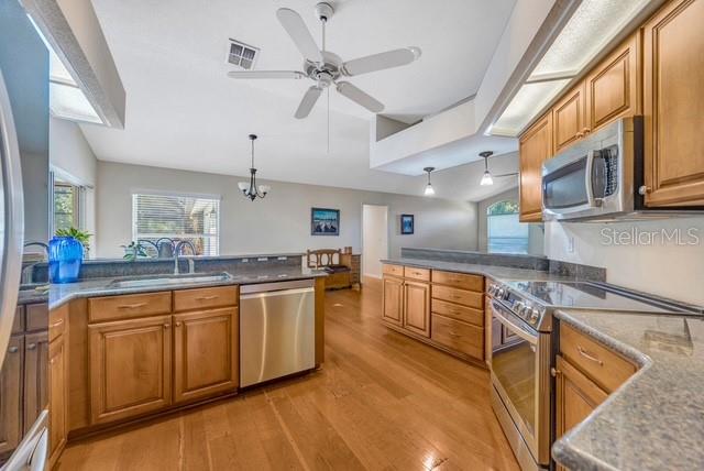 507 Surrey Lane Lutz, FL 33549 - Photo 5 of 27 a large kitchen with stainless steel appliances granite countertop a sink and dishwasher a stove with wooden floor