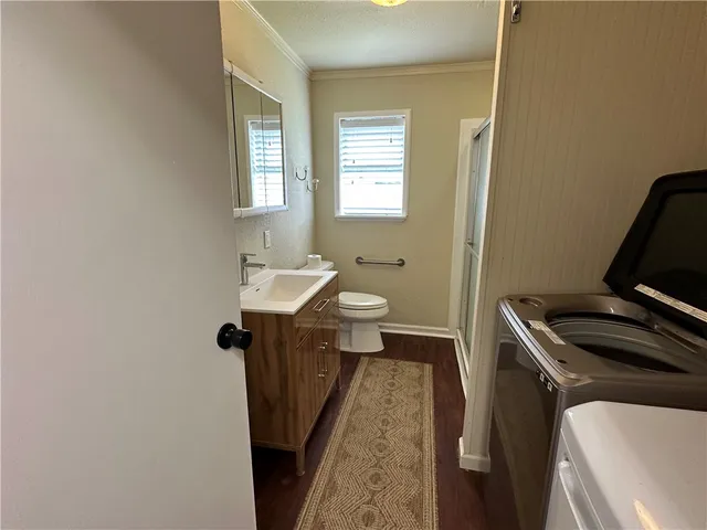 a bathroom with a sink a toilet a window and vanity