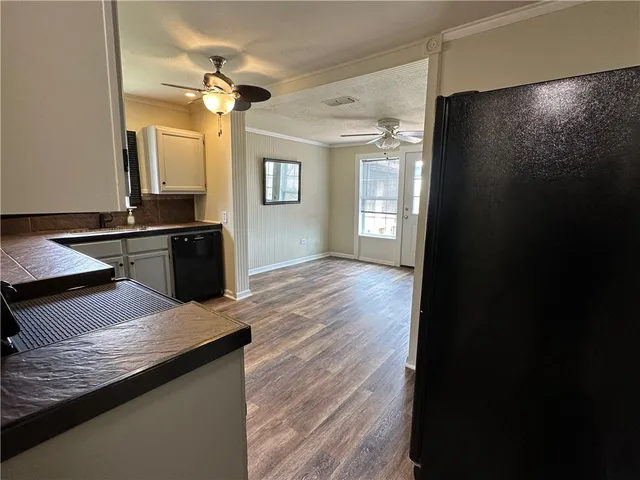 a kitchen with granite countertop a refrigerator a sink dishwasher and a stove with wooden floor