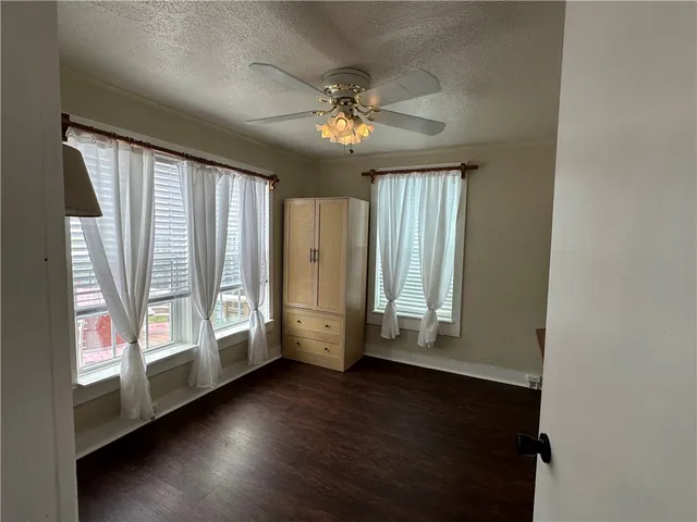 an empty room with wooden floor fan and windows