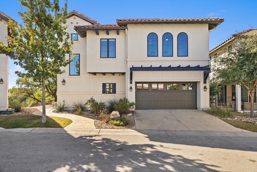 Mediterranean / spanish-style house with driveway, stucco siding, an attached garage, and a tiled roof