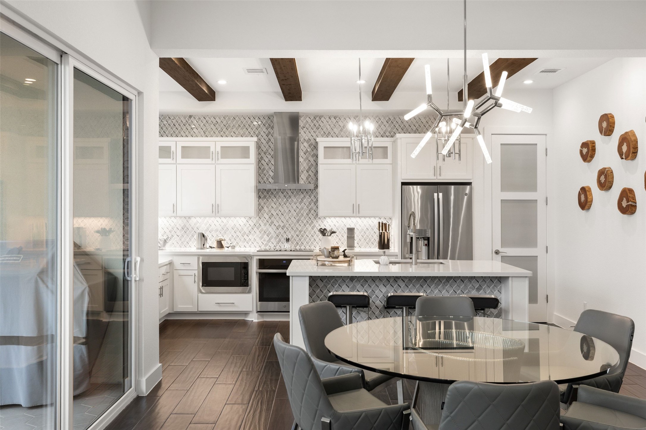 408 Rose Branch Way, Unit 24 Austin, TX 78738 - Photo 16 of 39 Kitchen with beamed ceiling, white cabinetry, decorative light fixtures, wood finish floors, and wall chimney exhaust hood