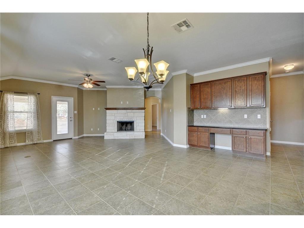 2109 Granite Springs Road Leander, TX 78641 - Photo 2 of 30 A spacious common area with tile flooring and a stone fireplace invites comfortable living.
