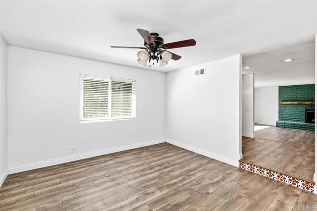 a view of an empty room with wooden floor fireplace and a window
