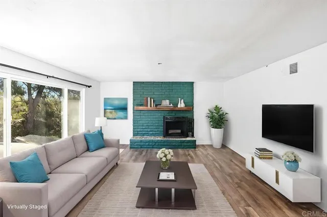 a view of an empty room with wooden floor a fireplace and a window