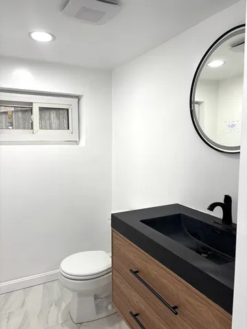 a bathroom with a toilet a sink and mirror