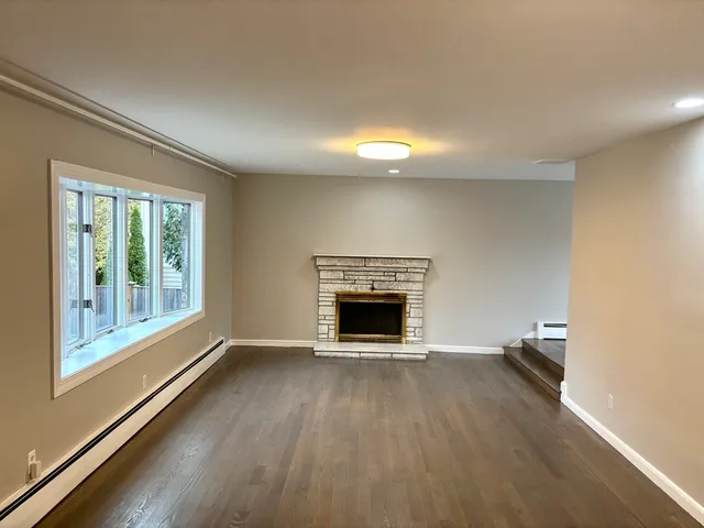 a view of an empty room with a fireplace and a window