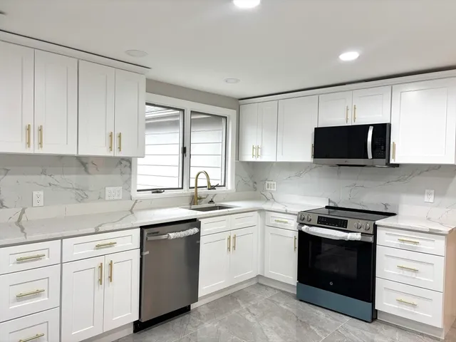 a kitchen with white cabinets and black appliances