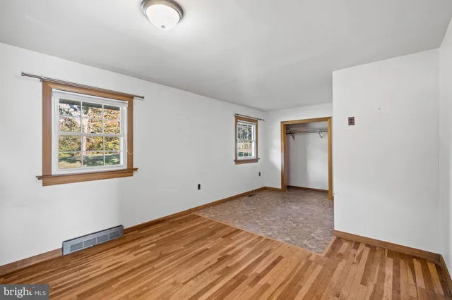 a view of an empty room with a window and wooden floor