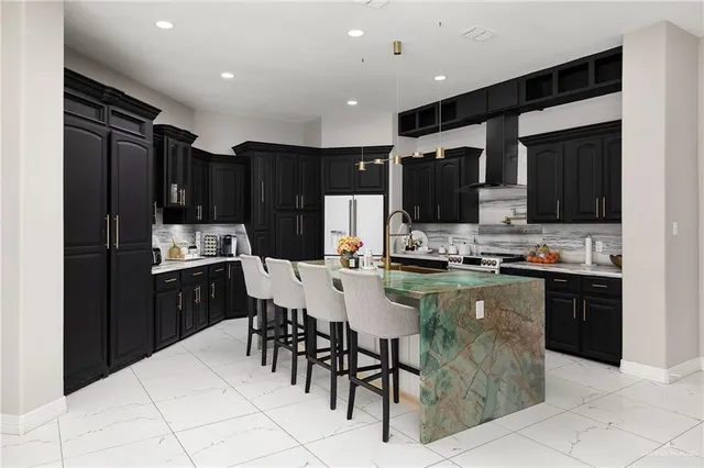 a kitchen with stainless steel appliances kitchen island granite countertop a refrigerator and a stove top oven