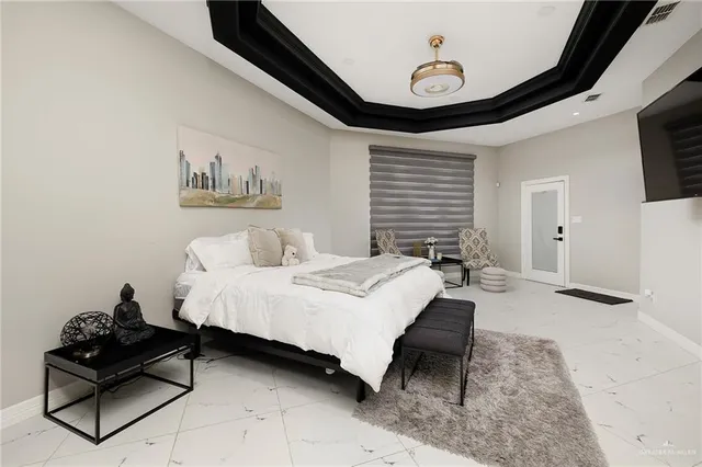 a spacious bedroom with a bed a rug and wooden floor