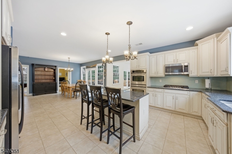 20 Sleepy Hollow Road Denville, NJ 07834 - Photo 17 of 49 a open kitchen with stainless steel appliances granite countertop a stove top oven a sink a dining table and chairs with white cabinets