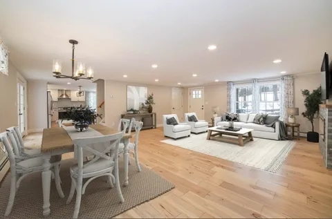 a view of a dining room and livingroom with furniture wooden floor a chandelier