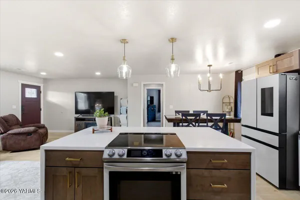 a kitchen with a refrigerator a stove a sink dishwasher a dining table and chairs with wooden cabinets