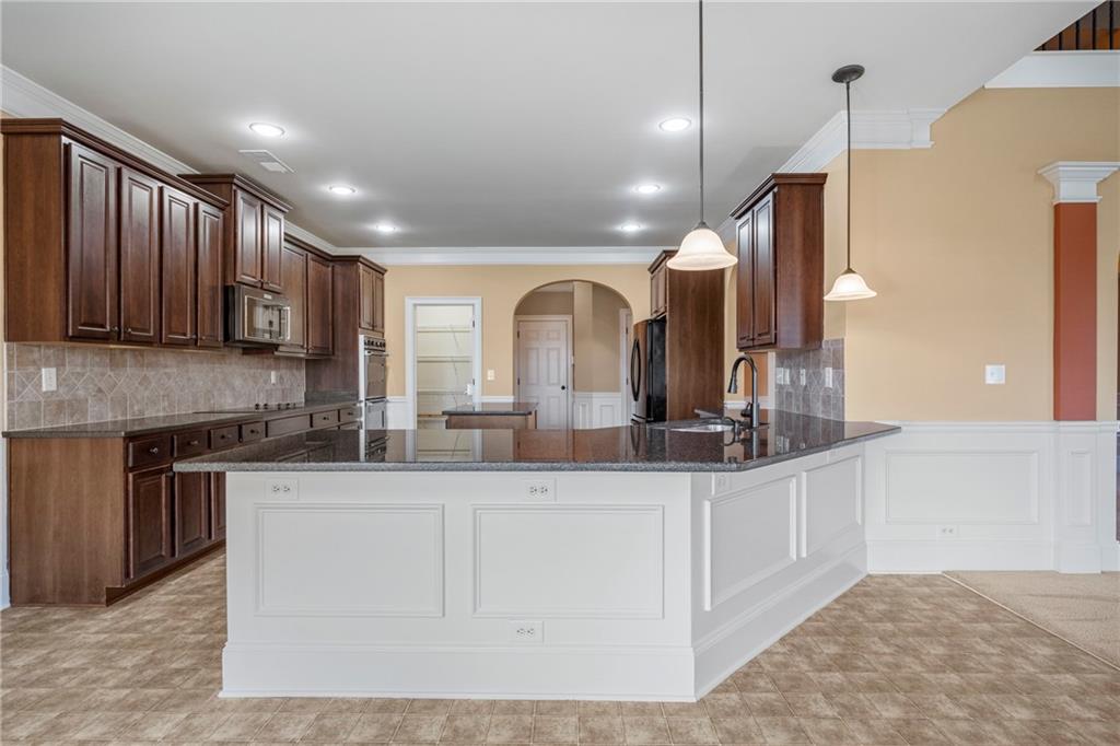 12 Juno Street Fort Mitchell, AL 36856 - Photo 8 of 43 Kitchen featuring arched walkways, tasteful backsplash, a decorative wall, dark stone counters, and ornamental molding