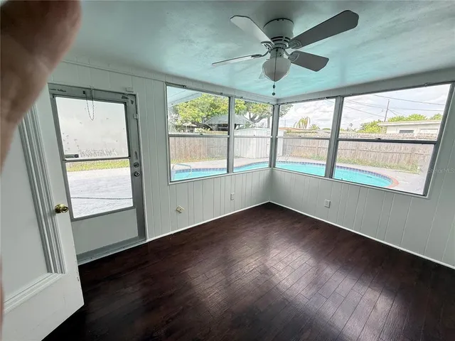 a view of an empty room with wooden floor and a window