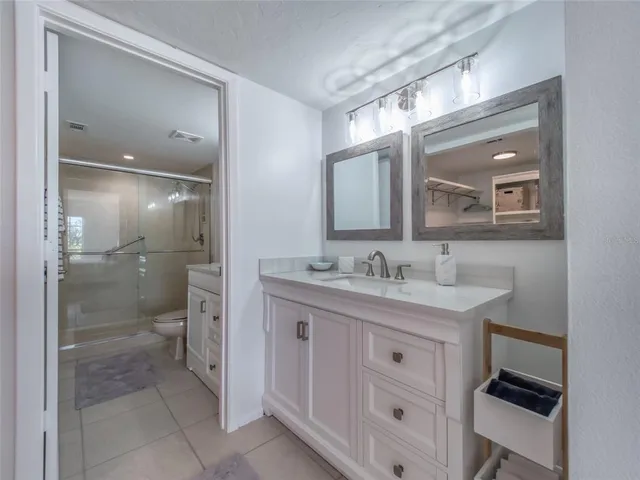 a bathroom with a granite countertop sink mirror and a shower
