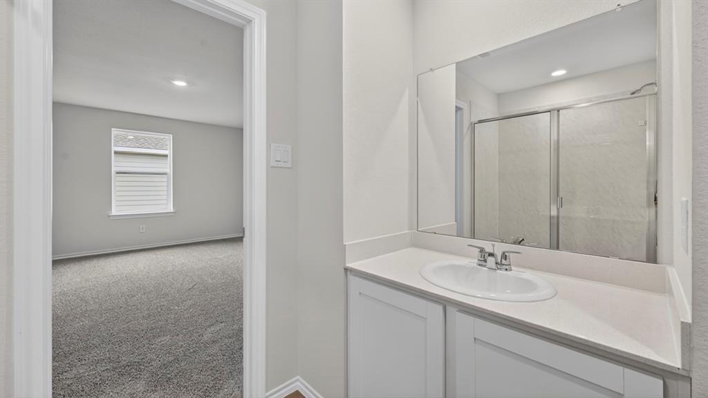 3534 Spring Time Street Forney, TX 75126 - Photo 14 of 24 Bathroom vanity featuring a single basin sink with a chrome faucet, a quartz-look countertop, and white shaker-style cabinetry