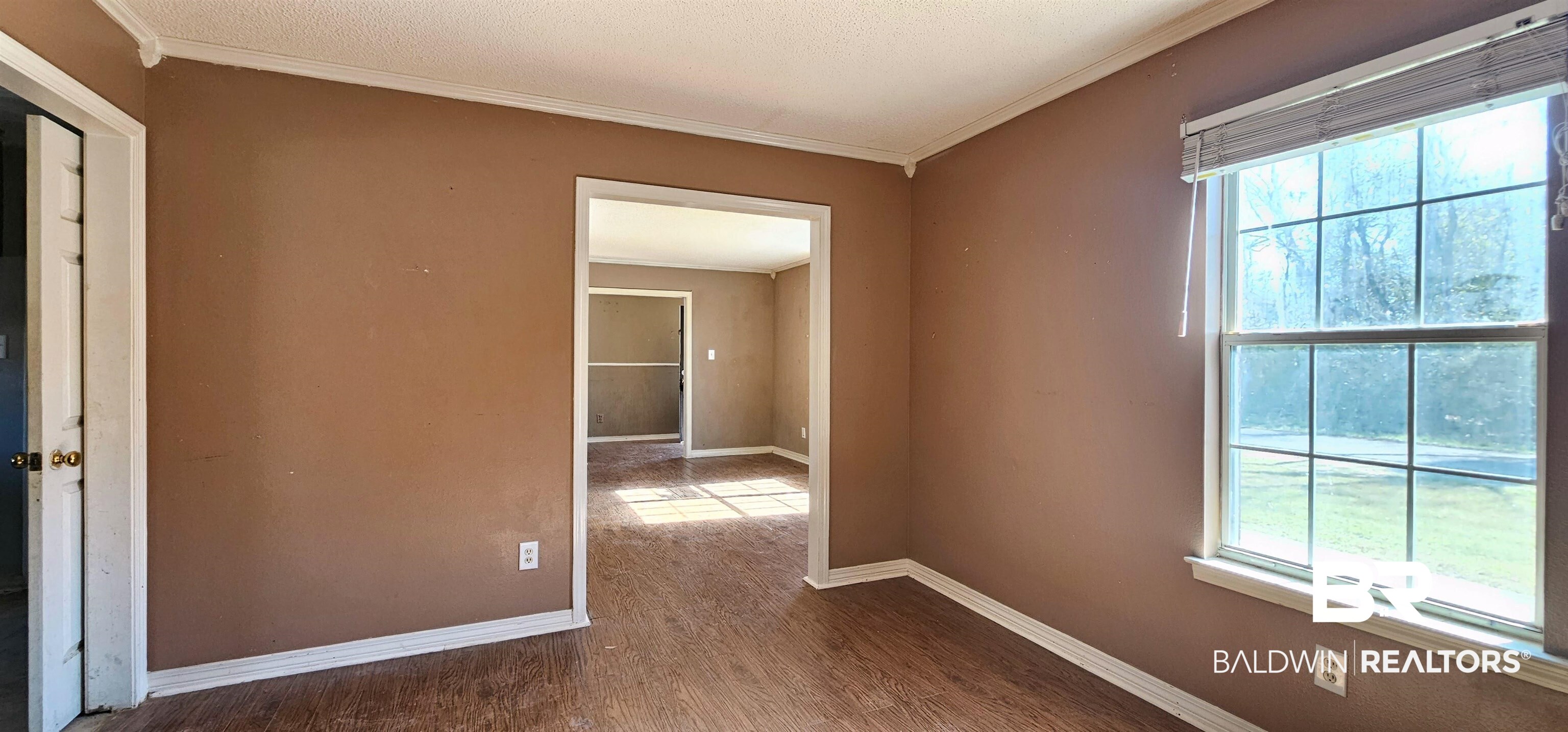 151 Bullard Street Atmore, AL 36502 - Photo 7 of 38 Unfurnished room featuring ornamental molding, dark wood-style flooring, and a textured ceiling