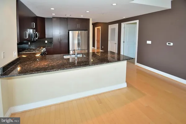 a view of a large kitchen with stainless steel appliances granite countertop a sink a stove and a refrigerator