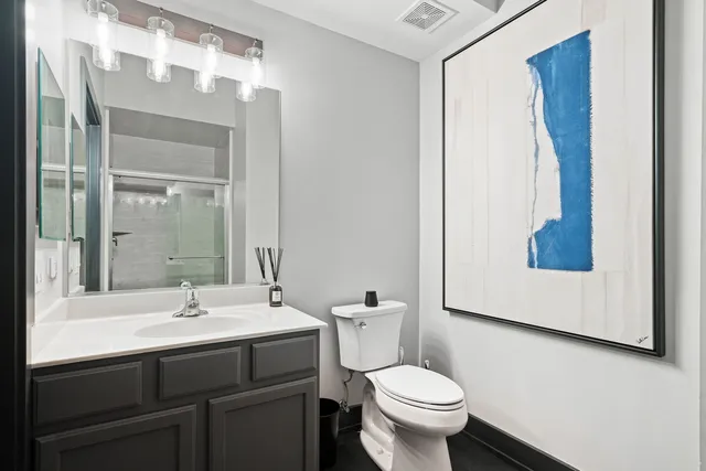 a bathroom with a sink mirror toilet and next to a window
