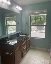 a bathroom with a granite countertop sink and a window