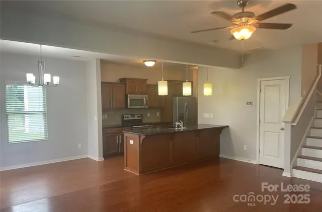 a view of a kitchen with kitchen island stainless steel appliances a sink and a chandelier