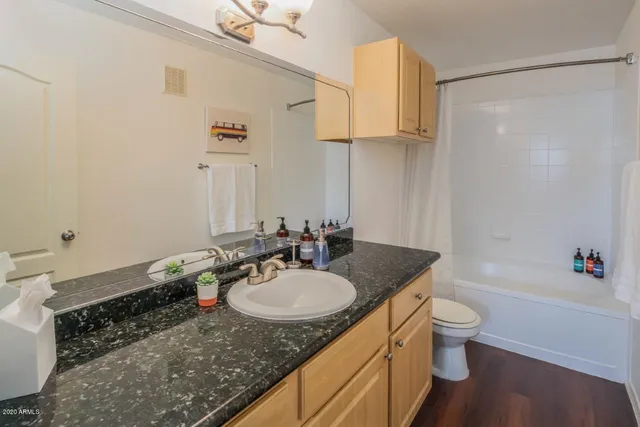 a bathroom with a granite countertop sink a toilet and bathtub