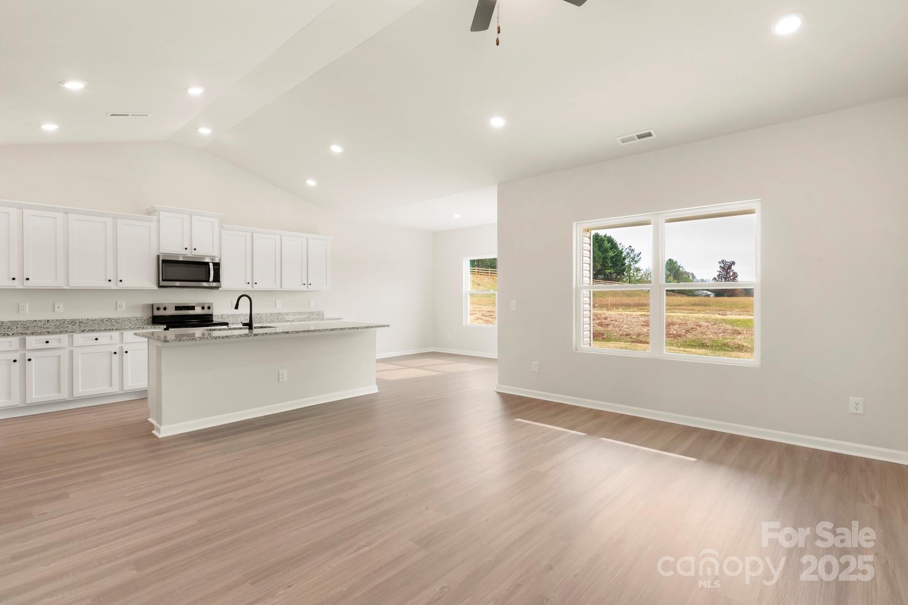 290 Limestone Terrace Apex, NC 27523 - Photo 5 of 11 a view of kitchen with granite countertop white cabinets and wooden floor