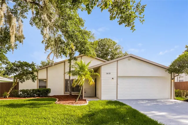 a view of a white house with a yard and potted plants