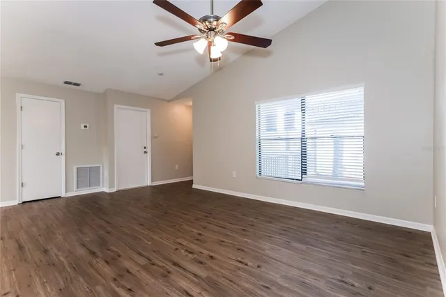 a view of an empty room with window and wooden floor