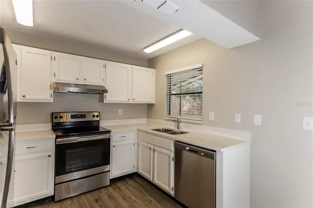 a kitchen with white cabinets stainless steel appliances and sink