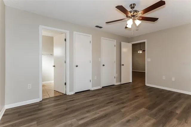 an empty room with wooden floor and a ceiling fan