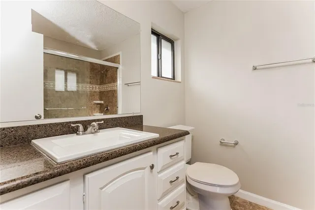 a bathroom with a granite countertop sink toilet and mirror