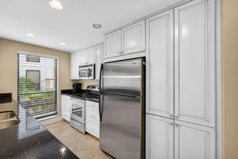 a kitchen with stainless steel appliances kitchen island granite top and refrigerator