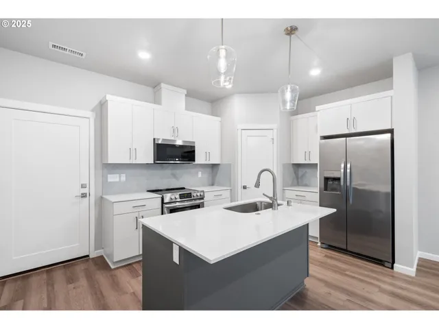 a kitchen with kitchen island a sink stainless steel appliances and cabinets