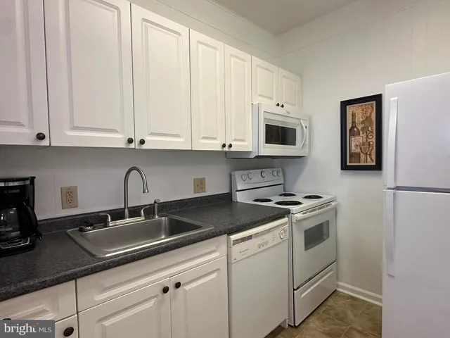 a kitchen with granite countertop a sink stove and microwave