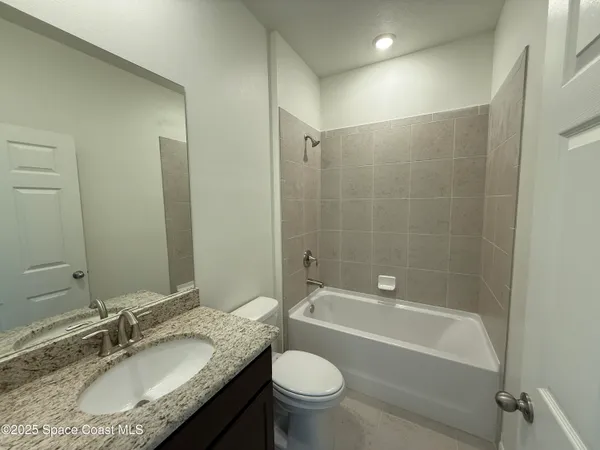 a bathroom with a granite countertop toilet a sink and a bathtub