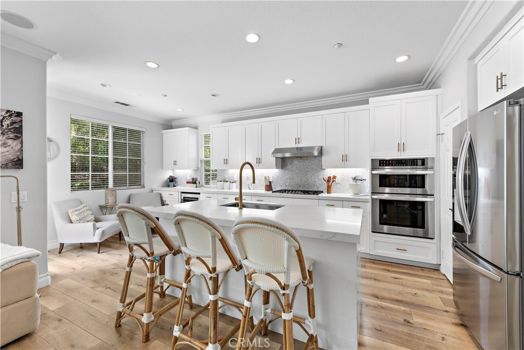 8 Bluewing Lane Ladera Ranch, CA 92694 - Photo 17 of 55 a kitchen with stainless steel appliances a stove a sink a refrigerator white cabinets and couches with wooden floor