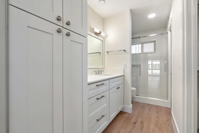 a bathroom with a double vanity sink a toilet and shower