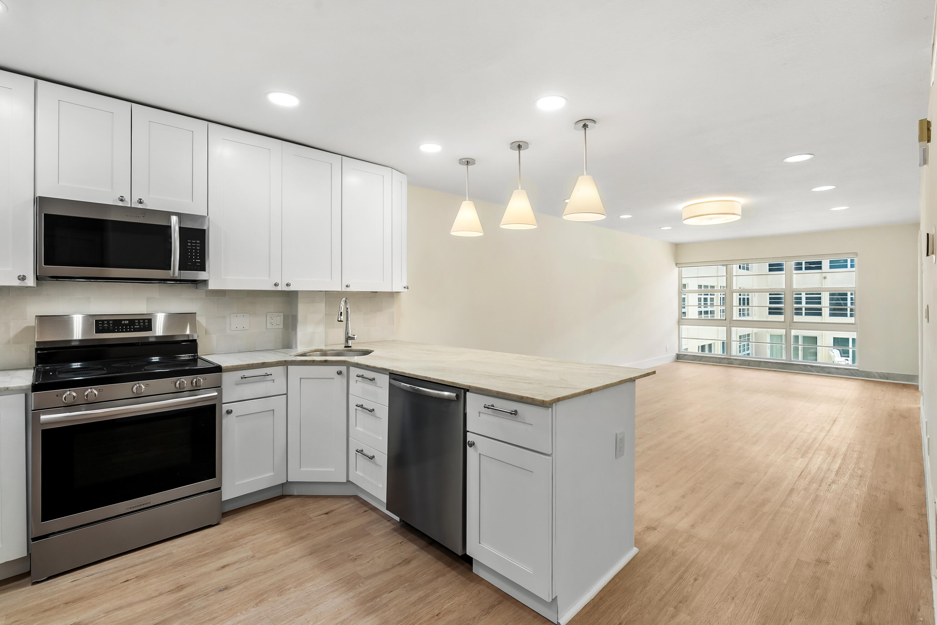 3851 North Ocean Boulevard, Unit 211 Gulf Stream, FL 33483 - Photo 3 of 19 a kitchen with granite countertop a stove and a wooden floor